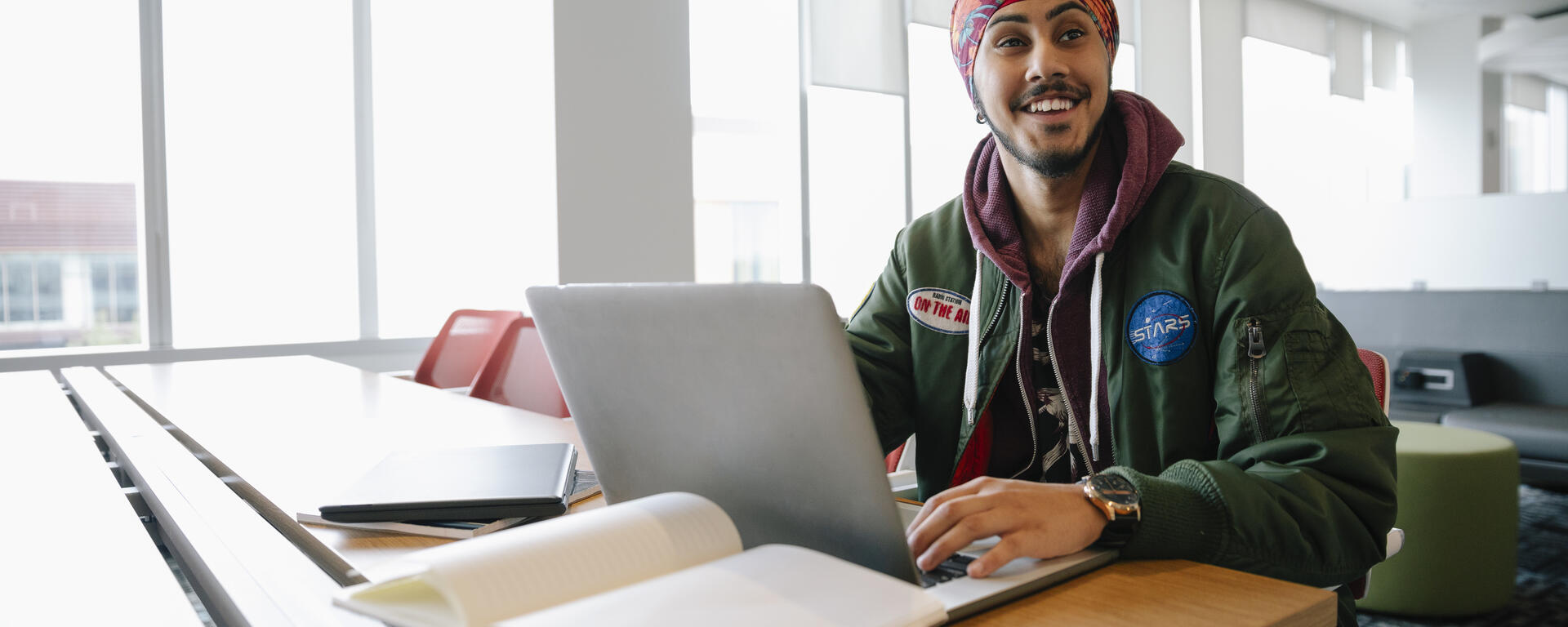 Young man wearing a pagri with a laptop and books, smiling